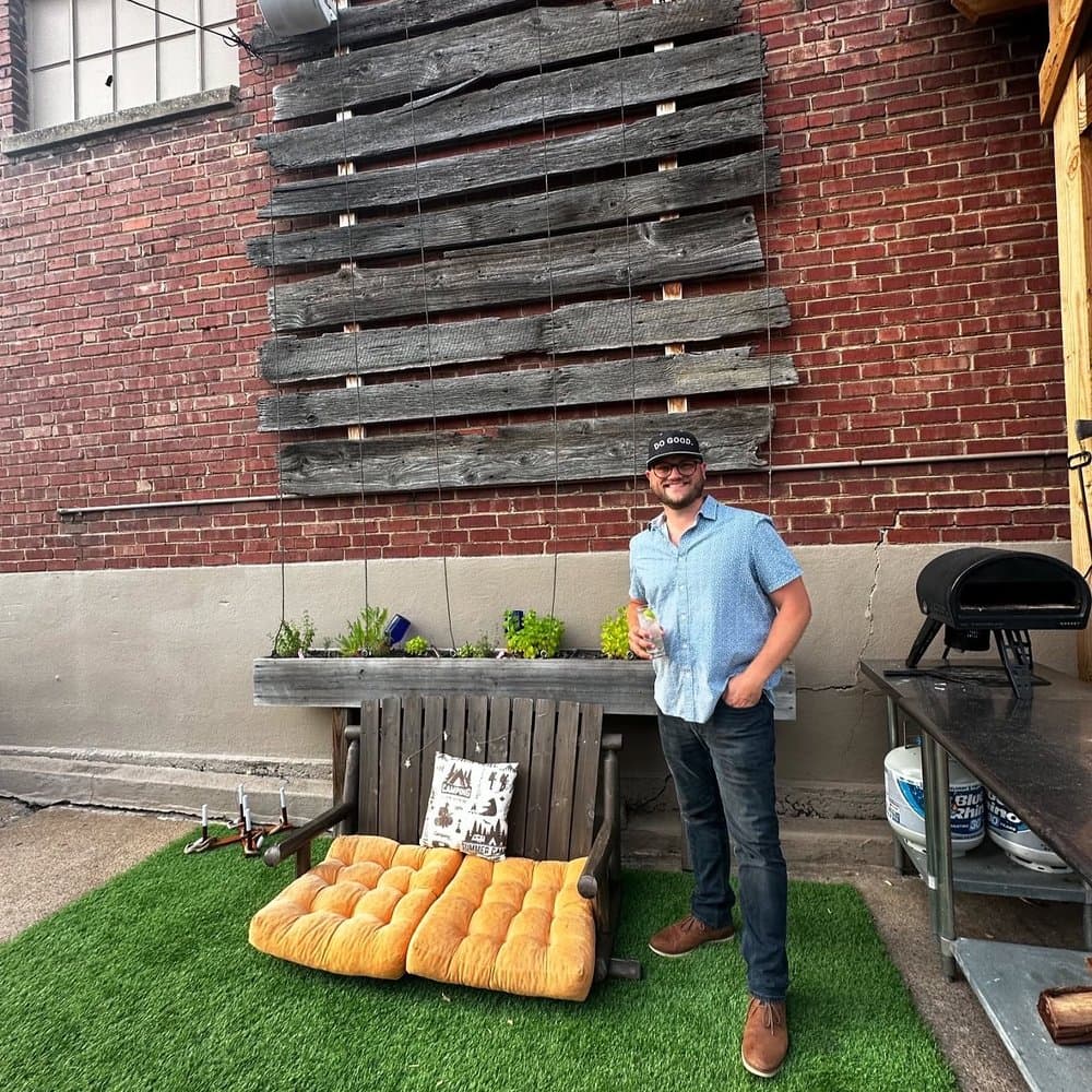 Ryan Jones outside in front of a pallet wall