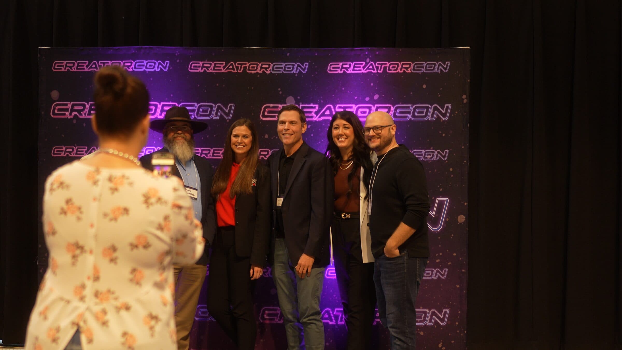 Group photo in front of CreatorCon's neon backdrop